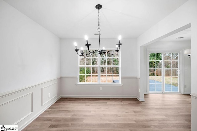 unfurnished dining area featuring a chandelier and light hardwood / wood-style floors