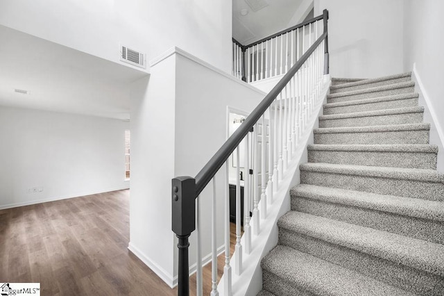 stairway with a towering ceiling and hardwood / wood-style flooring