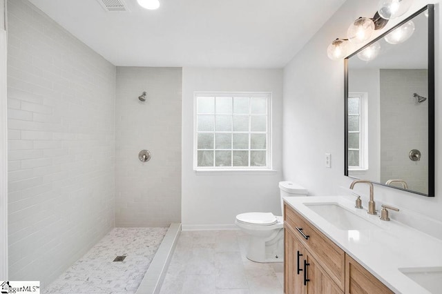 bathroom featuring tiled shower, tile patterned floors, vanity, and toilet