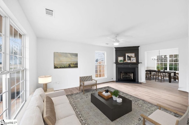 living room featuring hardwood / wood-style floors, a large fireplace, and ceiling fan