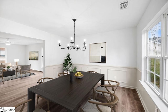 dining area featuring ceiling fan with notable chandelier, a healthy amount of sunlight, and wood-type flooring