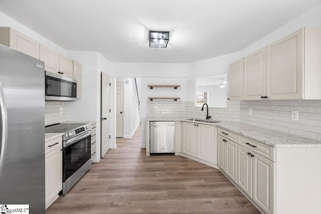 kitchen featuring sink, stainless steel appliances, light stone counters, white cabinets, and light wood-type flooring