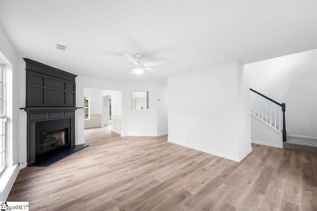 unfurnished living room with a fireplace, light hardwood / wood-style flooring, and ceiling fan