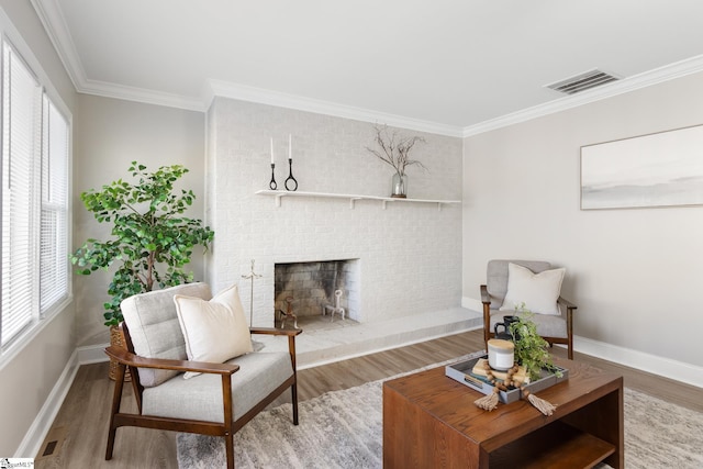 living area with hardwood / wood-style flooring, ornamental molding, and a fireplace