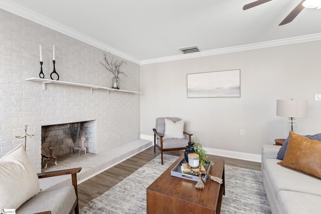 living room featuring ceiling fan, a fireplace, wood-type flooring, and ornamental molding