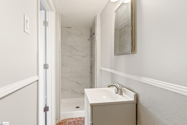 bathroom with vanity, a textured ceiling, and tiled shower