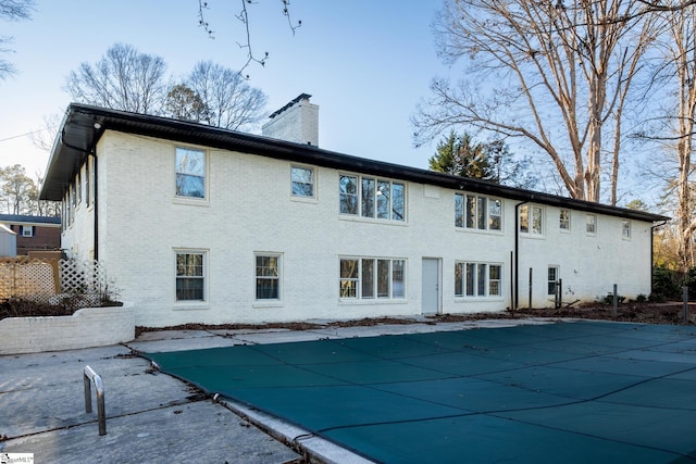 rear view of property with a patio and a covered pool