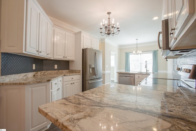 kitchen with appliances with stainless steel finishes, white cabinetry, hanging light fixtures, and sink