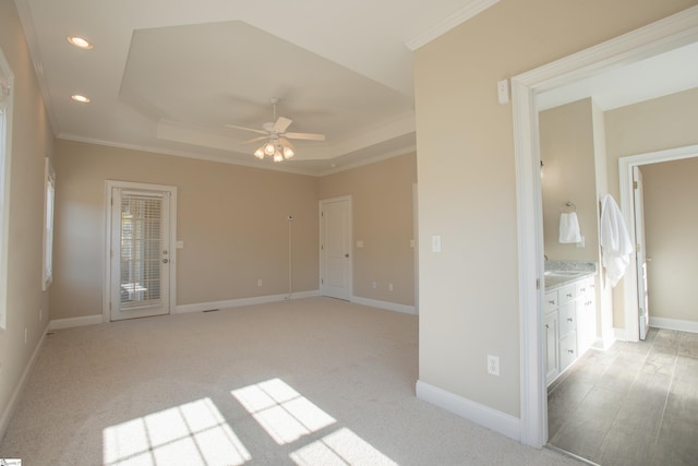 carpeted spare room featuring a tray ceiling, ceiling fan, and crown molding