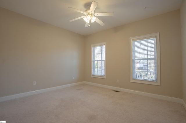 carpeted spare room featuring ceiling fan and a healthy amount of sunlight