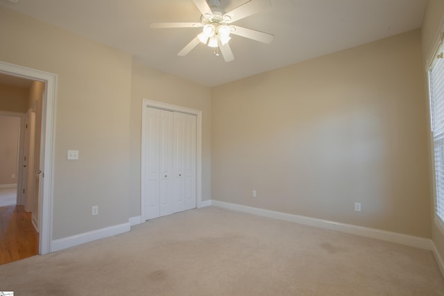 unfurnished bedroom featuring multiple windows, ceiling fan, a closet, and light colored carpet