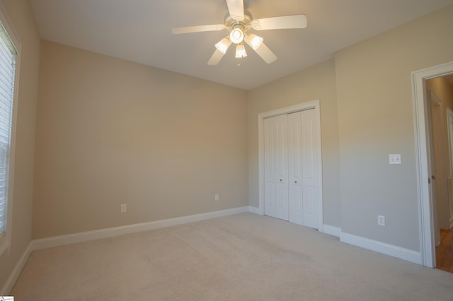 unfurnished bedroom featuring ceiling fan, a closet, and light carpet