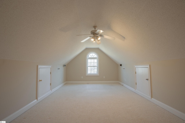 additional living space with a textured ceiling, ceiling fan, light colored carpet, and vaulted ceiling