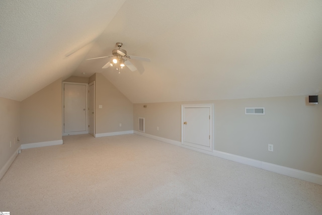 additional living space featuring a textured ceiling, light colored carpet, ceiling fan, and lofted ceiling