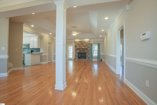 unfurnished living room featuring ceiling fan, decorative columns, a fireplace, and a tray ceiling