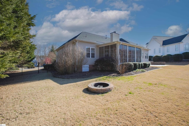 view of property exterior with a sunroom, an outdoor fire pit, and a lawn