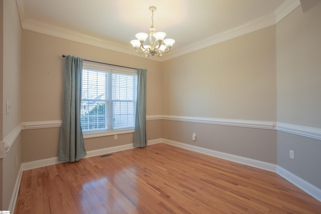 spare room with a chandelier, hardwood / wood-style floors, and ornamental molding