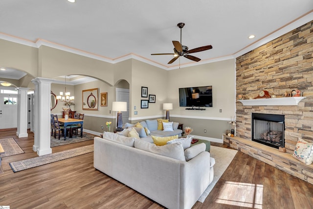 living room with a fireplace, wood-type flooring, ceiling fan with notable chandelier, and ornamental molding