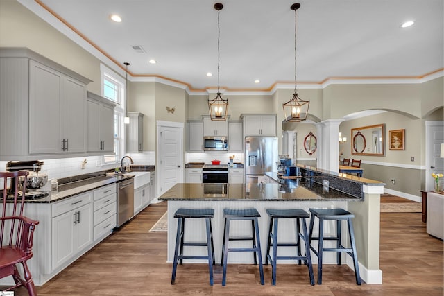 kitchen featuring decorative light fixtures, a spacious island, stainless steel appliances, and a breakfast bar