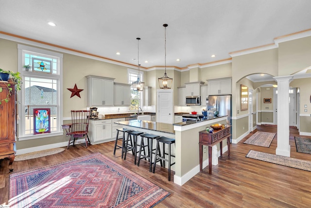 kitchen with a center island, pendant lighting, a breakfast bar area, appliances with stainless steel finishes, and hardwood / wood-style flooring