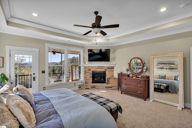 bedroom with a tray ceiling, a stone fireplace, ceiling fan, and access to outside