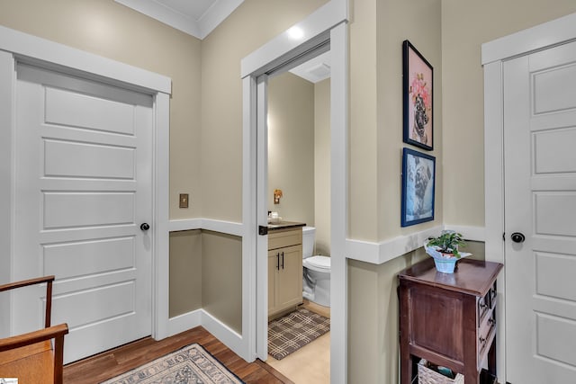 bathroom with crown molding, vanity, wood-type flooring, and toilet