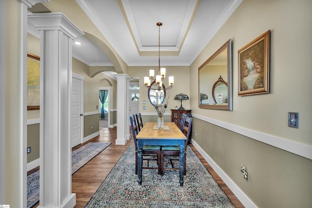 dining room featuring decorative columns, a raised ceiling, crown molding, an inviting chandelier, and dark hardwood / wood-style floors