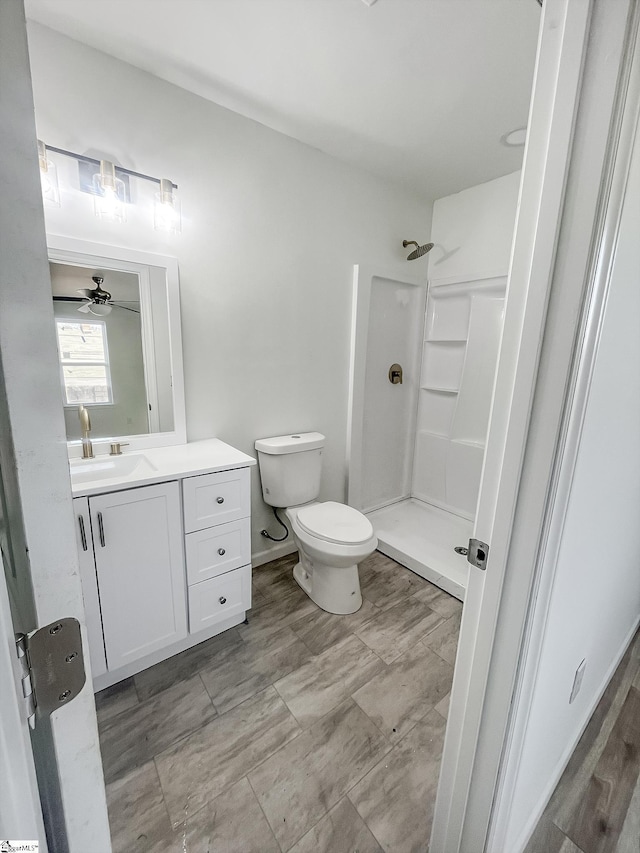 bathroom featuring ceiling fan, toilet, a shower, and vanity