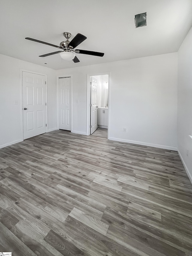 unfurnished bedroom featuring ceiling fan, ensuite bathroom, and hardwood / wood-style flooring