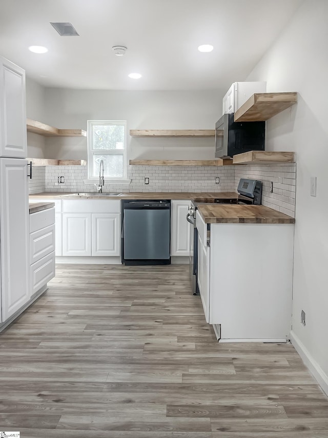 kitchen with wooden counters, white cabinets, sink, light hardwood / wood-style flooring, and appliances with stainless steel finishes