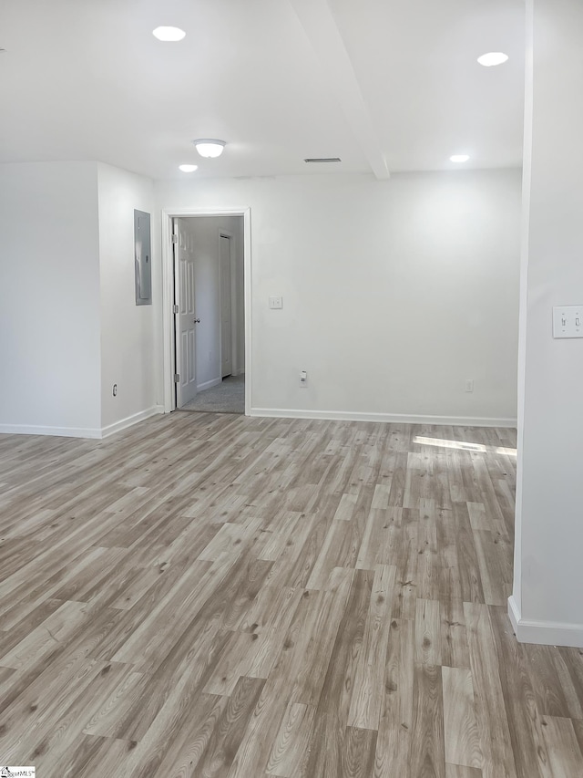 spare room featuring electric panel and light hardwood / wood-style floors