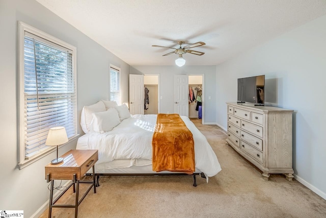 bedroom featuring a closet, a spacious closet, ceiling fan, and light colored carpet