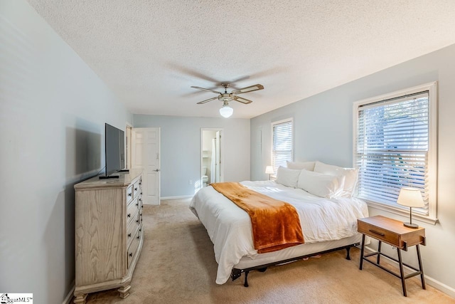 carpeted bedroom with multiple windows, a textured ceiling, ensuite bath, and ceiling fan