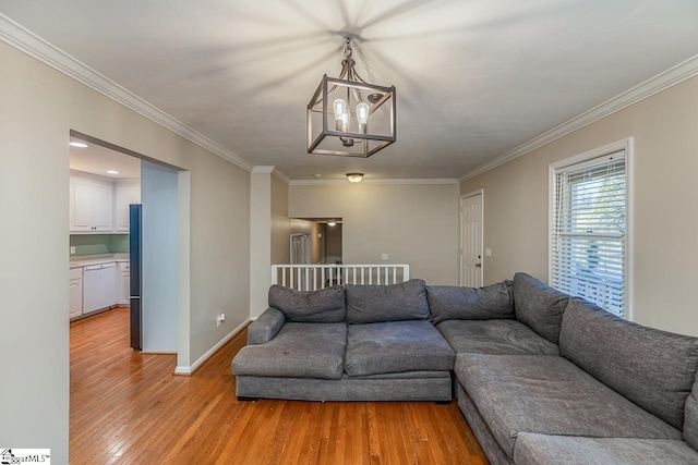 living room featuring a chandelier, light wood-type flooring, and ornamental molding