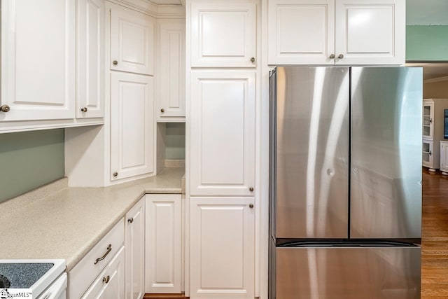 kitchen featuring white cabinets, stove, and stainless steel refrigerator