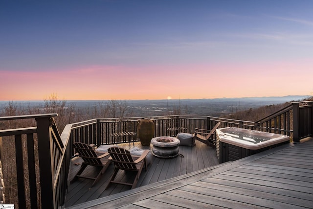 deck at dusk with a hot tub and an outdoor fire pit