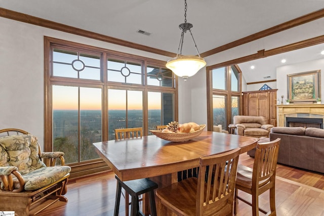 dining room with wood-type flooring, lofted ceiling, and ornamental molding