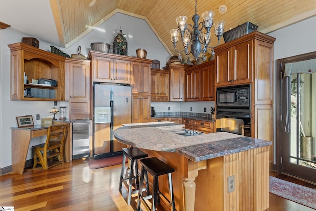 kitchen featuring an inviting chandelier, a kitchen breakfast bar, wine cooler, a kitchen island, and black appliances