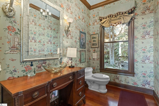 bathroom featuring an inviting chandelier, wood-type flooring, toilet, vanity, and ornamental molding