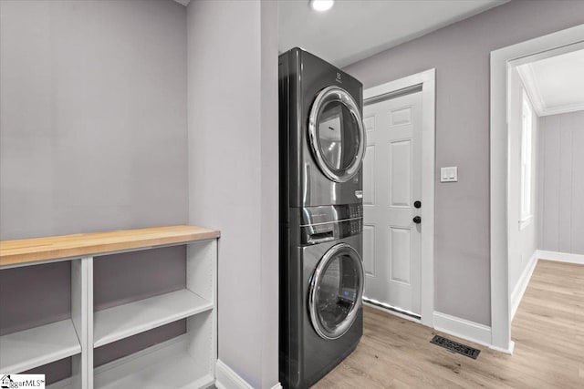 laundry area featuring stacked washer and dryer and light hardwood / wood-style floors