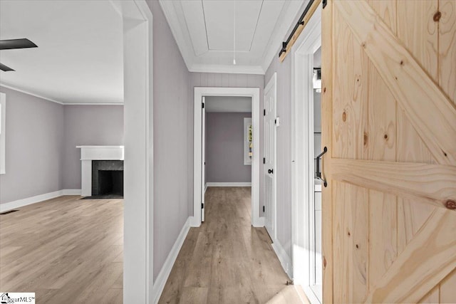 corridor featuring a barn door, light hardwood / wood-style floors, and ornamental molding