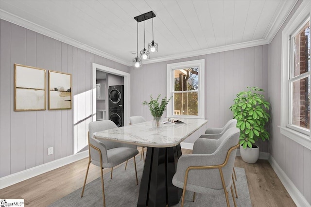 dining room with ornamental molding, stacked washer and dryer, light hardwood / wood-style floors, and wood ceiling