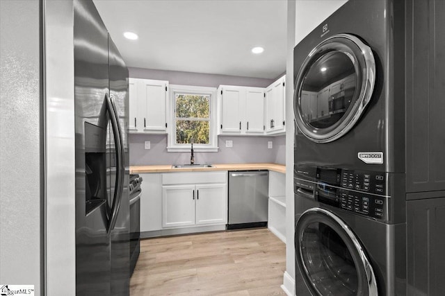 clothes washing area with light wood-type flooring, stacked washer / dryer, and sink