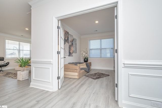 corridor with a healthy amount of sunlight, light hardwood / wood-style floors, and ornamental molding