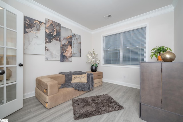 living area with wood-type flooring and crown molding