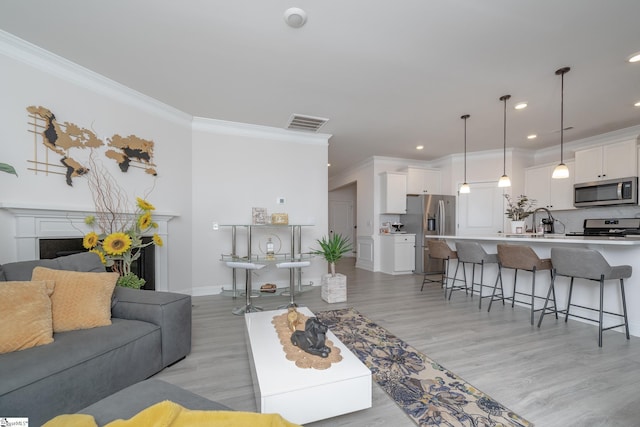 living room featuring light hardwood / wood-style floors, sink, and crown molding