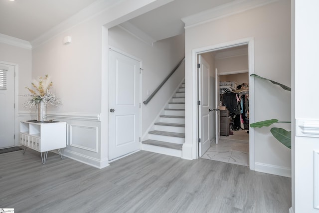 foyer entrance with crown molding and light hardwood / wood-style flooring