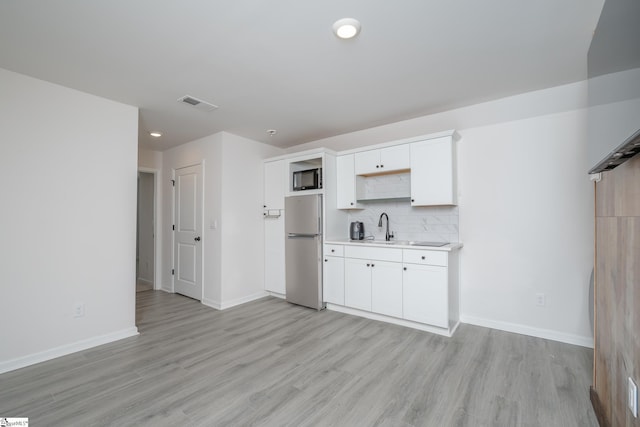 kitchen featuring decorative backsplash, stainless steel fridge, sink, light hardwood / wood-style flooring, and white cabinets