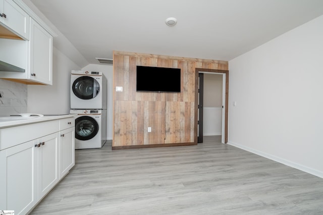 laundry room with cabinets, light hardwood / wood-style flooring, stacked washer / dryer, and sink