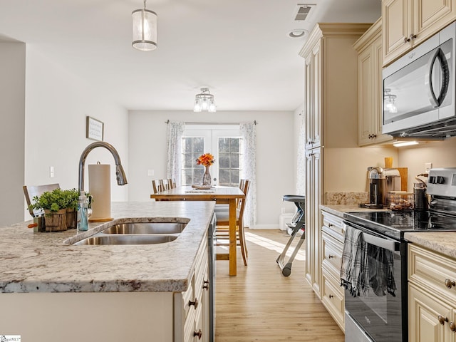 kitchen featuring sink, stainless steel range with electric cooktop, hanging light fixtures, and cream cabinets